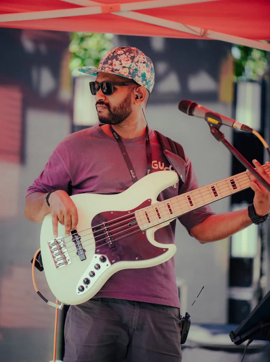 Arjun Mohan PC performing with a white bass guitar