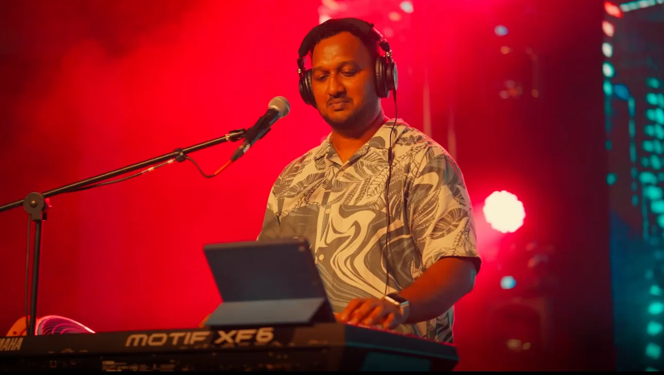 Sanjai Arakkal playing keyboards under red stage lighting